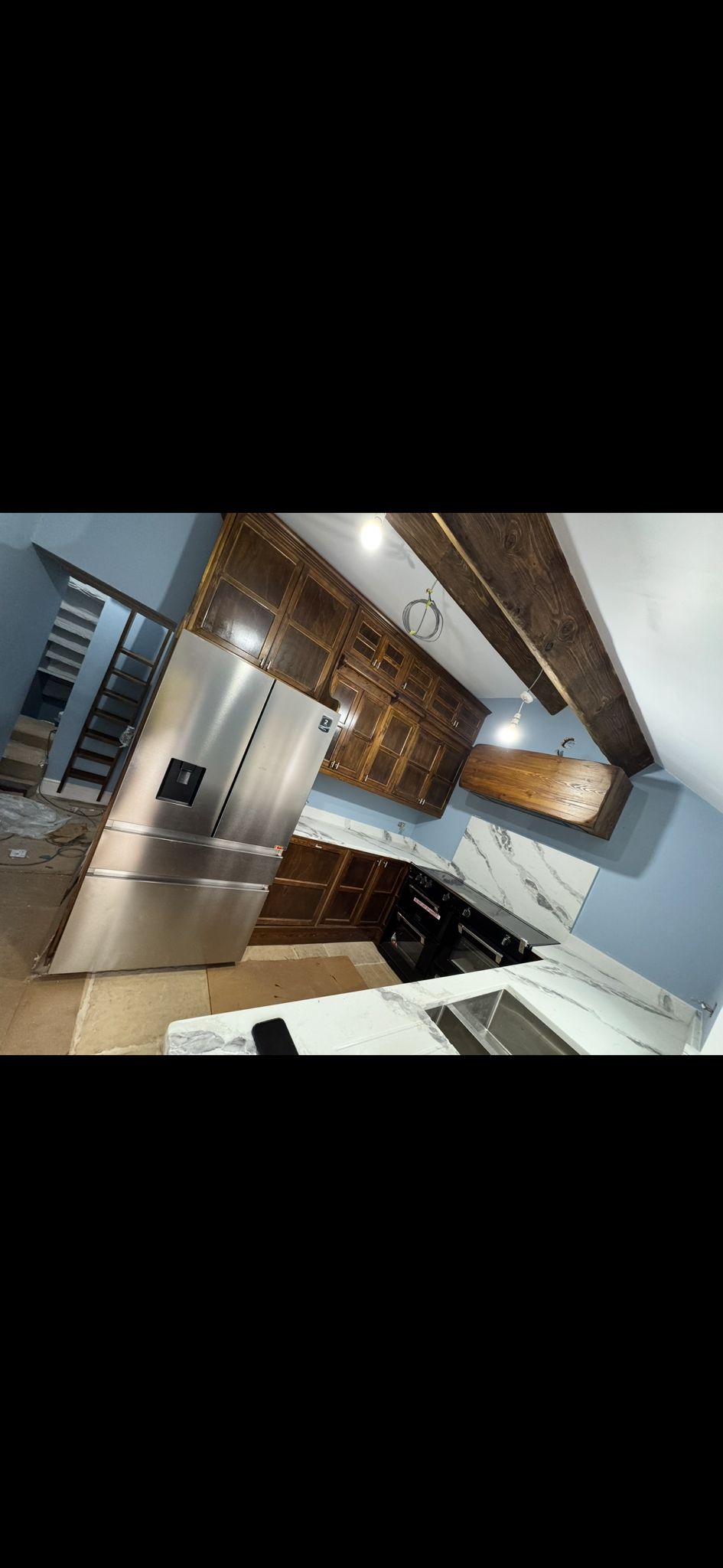 Handmade walnut kitchen with mullion-glass wall units, black range and marble worktops in a Yorkshire stone cottage
