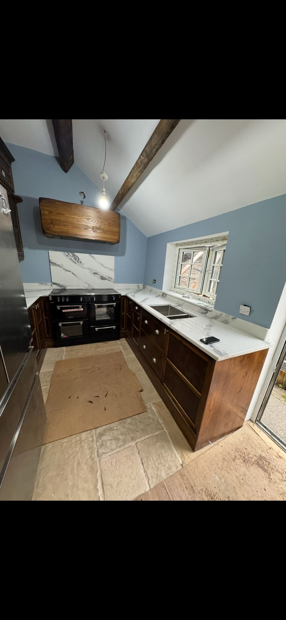 Handmade walnut kitchen with black range cooker, marble worktops and stone floor — installed in a Yorkshire barn conversion