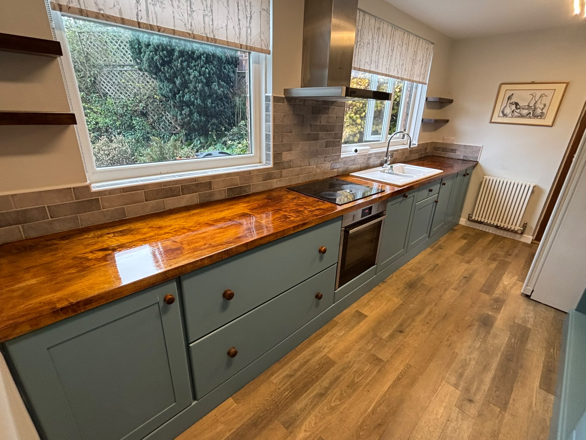 Handmade sage green Shaker kitchen with hand-painted units, wooden knobs, a glossy solid wood worktop and oak floor — Oak & Pine by Design, Yorkshire